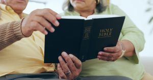 Hands, reading book or senior couple with bible, hope or support in Christianity religion for faith